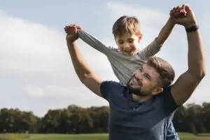 Father and son playing outdoors on Father’s Day, smiling and holding hands in the park
