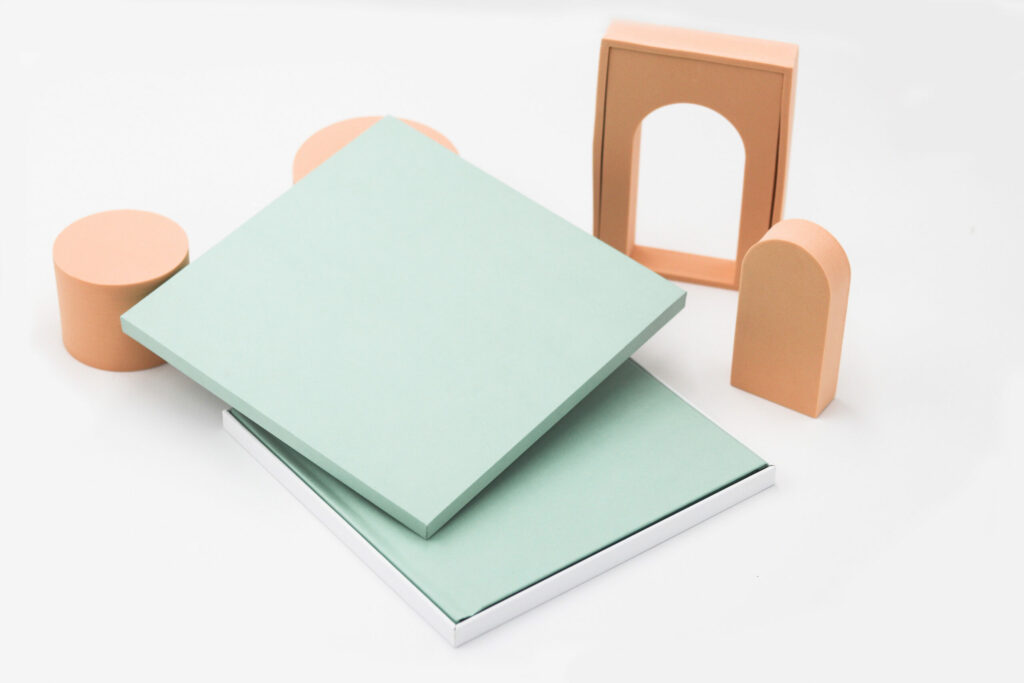 An open light-green square presentation box with a photobook of the same colour inside