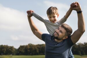 Father and son playing outdoors on Father’s Day, smiling and holding hands in the park